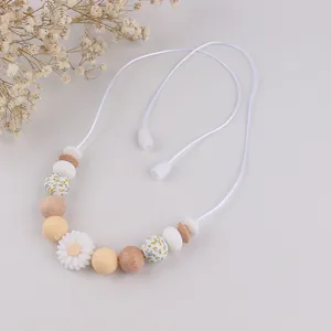 Detail of silicone and wood beads with daisy pendant on baby teething necklace