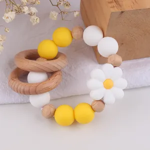 Detail of wooden rings and silicone daisy beads teething toy on natural linen background