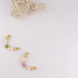 Detail of two silicone teething necklaces with colorful geometric beads and safety clasps
