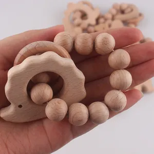 Close-up of baby grasping natural beech wood teething ring with hedgehog-shaped charm