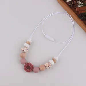 Detail of daisy silicone beads and wooden beads on a teething necklace for moms