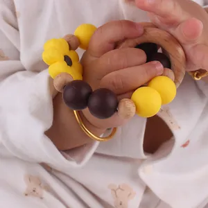 Close-up of baby hand holding sunflower silicone and beech wood rattle teething ring