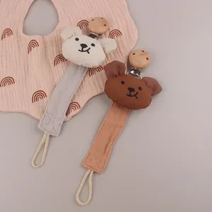 Detail of cartoon bear cotton pacifier clips in cream and brown with natural wood clamps