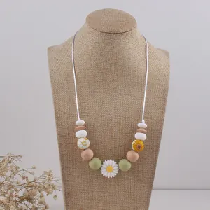 Bohemian daisy teething necklace featuring silicone and natural wood beads on a model stand