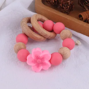 Macro view of newborn beech wood and pink silicone flower teething bracelet toy