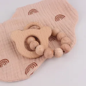 Detailed close-up of beech wood bear teether and polished beads on muslin fabric