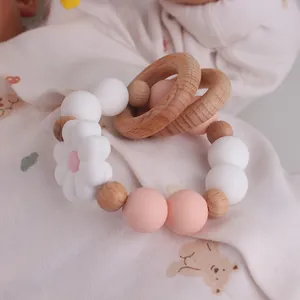 Detail of wooden rings with pink silicone beads and a daisy pendant for baby teething
