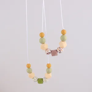 Detail of floral printed and geometric silicone teething beads on a nursing necklace