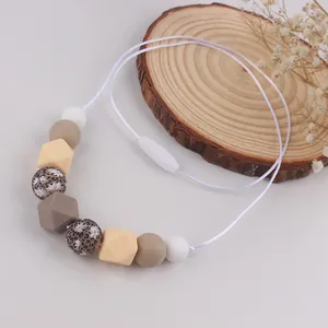 Detail of silicone teething necklace with geometric beads on a natural wooden slice