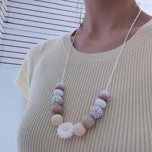 Detail of daisy silicone beads and natural wood beads on a boho baby teething necklace