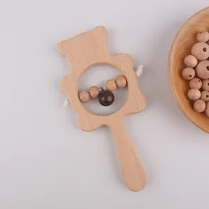 Macro shot of bear-shaped beech wood baby rattle with beads and a metallic bell