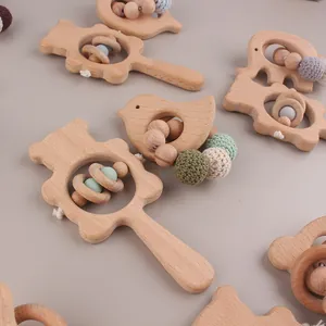 Detail of handcrafted beech wood baby rattles with cute animal shapes and knit beads