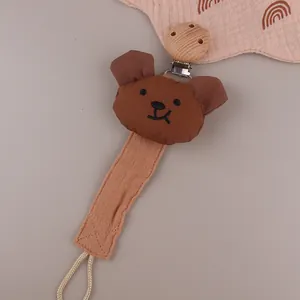 Detail of baby pacifier clip featuring a brown plush bear head and a round wooden clip