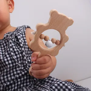 Détail du hochet ours en bois avec clochette, tenu par un bébé dans une scène réelle