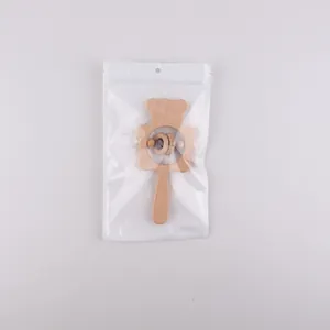 Détail d'un hochet ours en bois dans un emballage plastique sur fond gris neutre