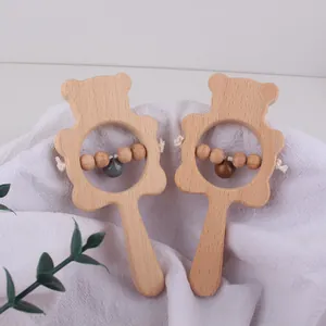 Detail of two-piece beech wood baby bear rattles with colorful bells on soft linen fabric