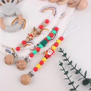 Close-up of three silicone pacifier clips with festive Santa and reindeer beads