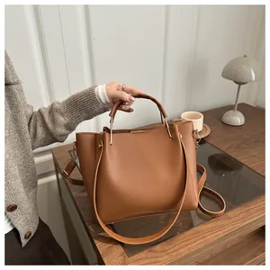Détail du sac cabas en cuir grainé caramel avec ferrures dorées sur une table en bois