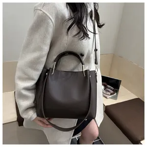 Détail du sac cabas marron à texture litchi avec anneaux dorés et bandoulière
