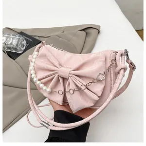 Close-up of pink crescent bag featuring a large bow and elegant pearl handle strap