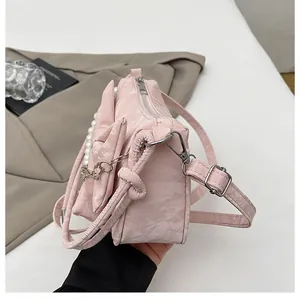 Close-up of light pink bow handbag with elegant pearl accents and pleated texture