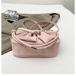 Detail of pink bow handbag featuring a large ribbon and elegant pearl carry handle