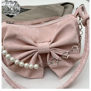 Close-up of pink bow handbag featuring pearl chain and floral metal strap details