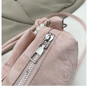 Close-up of pink pleated leather bag with silver zipper and pearl handle detail