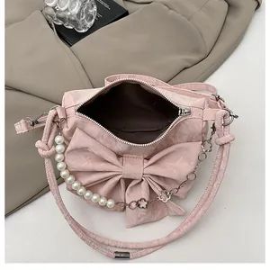 Detailed top view of pink bow handbag showing pearl handle and interior storage