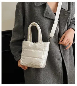 Détail d'un sac matelassé blanc brillant avec bandoulière et ferrures argentées sur modèle