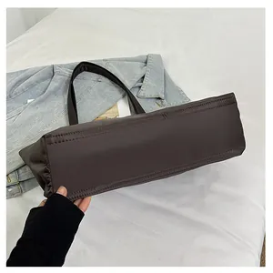 Detailweergave van de brede rechthoekige basis en stiksels van deze bruine nylon shopper