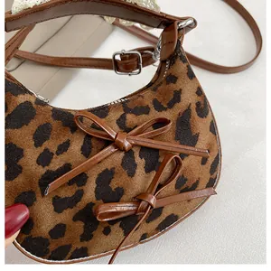 Dettaglio della borsa leopardata con fiocchi in pelle e finiture in pizzo bianco