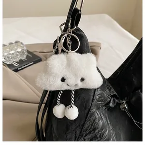 Vue détaillée du charme nuage en peluche blanche avec sourire sur un sac noir plissé