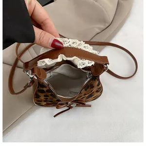 Dettaglio mini borsa leopardata con pizzo, fiocco e cerniera interna in primo piano