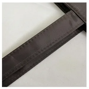 Detailopname van de versterkte stiksels op de schouderriem van de bruine nylon draagtas