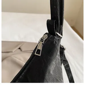 Détail du sac noir avec texture plissée vintage et fermeture à glissière en métal argenté