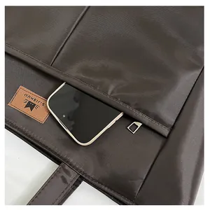 Detailopname van de donkerbruine shopper met geweven textuur en smartphone in het voorvak