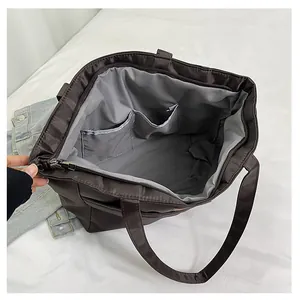 Binnenzicht van de bruine nylon draagtas met grijze voering en twee binnenzakken