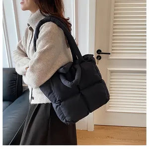 Close-up of lightweight black quilted tote bag showing soft puffer texture and long handles