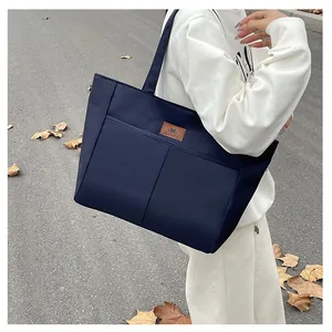 Détail d'un grand sac fourre-tout bleu marine avec poches frontales et écusson en cuir