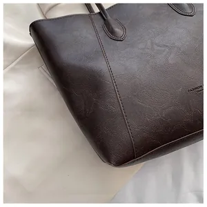 Nahaufnahme einer braunen Tragetasche mit FASHION-Text und feinen Nähten auf dem Leder