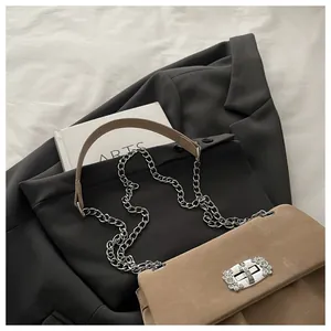 Détail du sac en cuir nubuck camel avec fermoir strass sur une veste de blazer grise