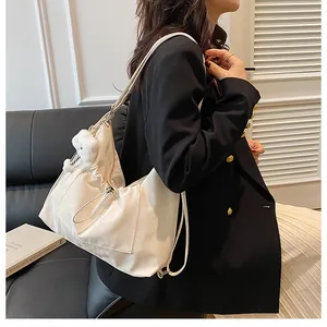 Détail d'un sac à bandoulière blanc avec cordon de serrage et charmant ours en peluche