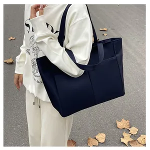 Detail van donkerblauwe tote bag met verticale stiksels en brede schouderbanden