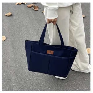 Detail van de marineblauwe draagtas met multi-pockets en lederen logo op stevig materiaal