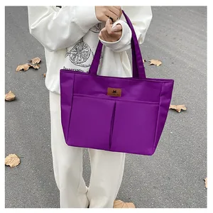 Detail van de paarse shopper met voorzakken en leren merklogo op fijn nylon weefsel