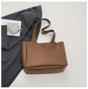 Detail showing the brown faux leather tote bag with vertical stitching and smooth shoulder strap