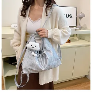 Gros plan du sac bandoulière argenté plissé orné d'un joli pendentif en forme de nuage