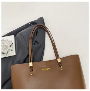 Detailed top view of large brown leather tote bag with gold hardware and fashion text