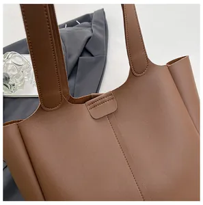 Macro detail of the brown leather tote bag with double stitched handles and seams